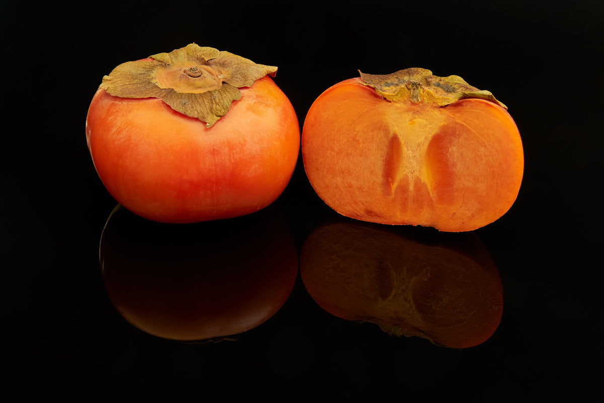 Fuyu persimmon fruit, one whole and one cut open